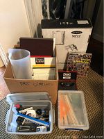 Overall view of boxed easel, canvases, storage tube, sketchbooks and plastic totes