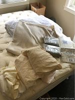 Bedding items laid out on mattress including sheets, bed skirt, mattress pad, and blanket