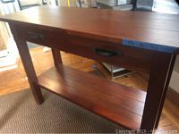 View of dark wood sideboard showing flat top surface, drawer with metal handles, legs, and lower shelf
