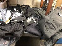 Photo showing assortment of black motorcycle pants, jackets, gloves and boots laid out on a table