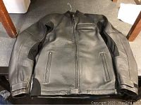 Black Aerostich leather Transit jacket laid flat showing front zip, pockets and sleeve vents