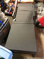 Chaise lounge chair with grey cushion covering it, view of entire lounge horizontally placed.