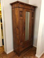 Full front view of armoire showing overall design, inlay, mirror, drawer and feet.