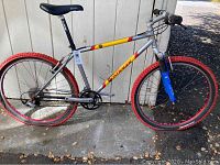 Full side profile of silver Bontrager bike with yellow/red accents, 16-inch frame, red tires and rims