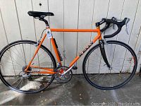 Full side view of the orange Kelly road bike showing frame, wheels, pedals and bottle cage