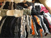 Wide view of mostly folded women's pants and tops in colors including beige, black, gray, and red