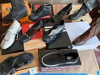 Overview of nine pairs of shoes on boxes: boots, pumps, sneakers, sandals
