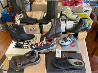 Overview of various footwear on boxes including boots, sandals, cycling shoes, running shoes