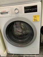 Front view of Bosch washer showing control panel, detergent drawer, and circular door with silver ring