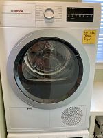 Front view of white Bosch front-load dryer with control panel and large glass door.