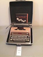 Full front view of Royal Futura 800 portable typewriter in hard case with user manual displayed upright behind the typewriter.