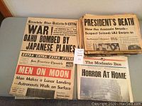 Multiple vintage newspapers featuring major historical headlines from Pearl Harbor bombing, JFK assassination, and moon landing.