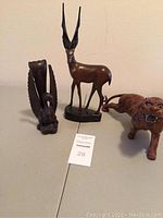 Photo of three carved animal figurines on a table including a swan, antelope, and tiger.