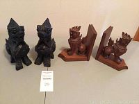 Photo showing both pairs of carved figures: the dark gargoyle figures and the wooden bookends.