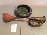 Both items side by side: copper bowl and brass horn with bulb