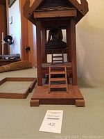 Frontal view of wooden temple with seated Buddha, showing base, front stairs, and interior Buddha figure