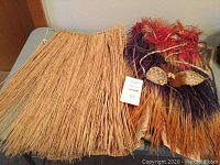 Grass skirts and a decorative top with seashells and feathers laid out on a surface.