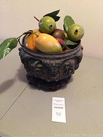 Decorative Thai silver bowl filled with assorted vintage artificial fruit on a surface with a lot number card in front.