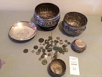 Overview of two medium bowls, two small bowls, dish and pile of coins laid out on table