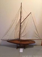 Model sailboat with detailed rigging, wooden hull, and white sails viewed from the side.