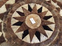 Close-up top view of a round alpaca skin rug displaying the star pattern in shades of brown, black and cream.