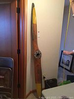 Full view of two-blade wooden propeller leaning against wall