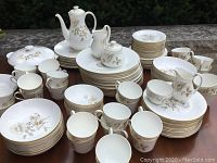 Overview of set showing stacks of dinner plates, bowls, teacups, saucers, coffee pot, creamer and sugar bowls