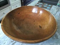 Photo of the large wooden bowl showing interior, patina and wear marks on a countertop.