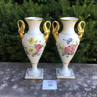 Front view of two vases on stone surface with foliage background