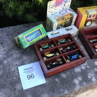 Wide view of lot showing wooden display case with miniature vintage cars, boxed vintage car replicas, and boxed tractor and NASCAR car toys.