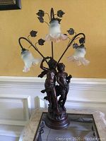 Front view of lamp showing cherub sculpture base and three floral glass shades