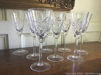 Eight champagne flutes with pinwheel cut crystal pattern on long stems and round bases.