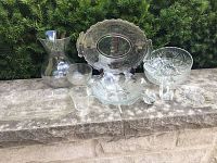 Overview of all glassware items including plates, bowls, vase, and glasses arranged on a stone ledge