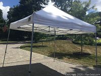 Assembled exterior view of white canopy tent with metal frame on lawn