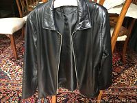 Front view of the black leather jacket showing zipper, collar, and smooth leather texture.