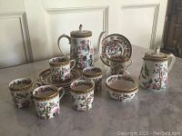 Full display of tea service set including cups, saucers, teapot, creamer, and sugar bowl