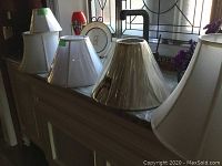 Five silk lampshades displayed on a surface, showing variety in size and shape.