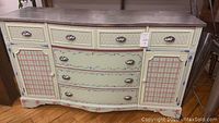 Front view of the hand painted dresser showing floral and lattice patterns with metal handles and knobs