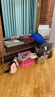 Lot showing handbags, backpacks on window ledge and floor against a brick wall and vertical blinds