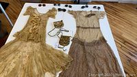 Overview of two tiered lace dresses, four pairs of sunglasses, and two gold-tone sequin mesh bags on table