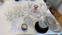Overview of crystal and colored glassware including wine glasses, candlesticks, candy dish, and small plates.