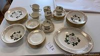 Full view of the Homer and Laughlin Victoria Rose china service spread on a white table showing plates, bowls, cups, saucers, creamers, and serving platter