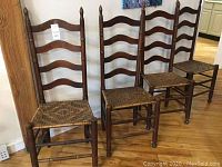 Full view of the set of three antique handwoven ladder back chairs showing wood frames, woven seats, and overall style.