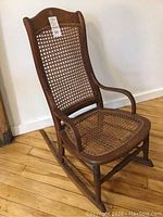 Front view of vintage wooden rocking chair showing cane backrest and seat