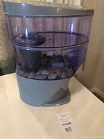 Full view of the Nikken water filter showing the purple reservoir and gray base with stones inside the reservoir.