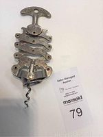 Top view of vintage metal corkscrew opener showing zigzag mechanism and T-handle stamped with 'ZIG ZAG'.