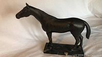 Side view of the metal horse statue on marble base, showing overall shape and size.