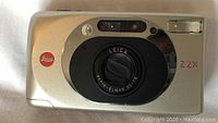 Front view of Leica Z2X showing the Vario-Elmar lens, rangefinder window, and flash.
