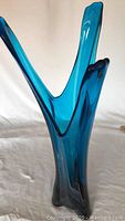 Angled close-up of the blue glass vase showing the three elongated upward prongs and glossy finish.