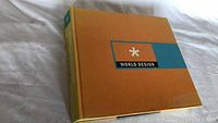 Front cover of World Design book showing orange cover with blue and black panel with title.